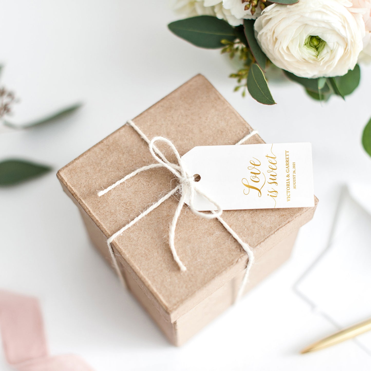 Lux Party’s white love is sweet wedding favor tag with gold script, tied to a brown kraft favor box.