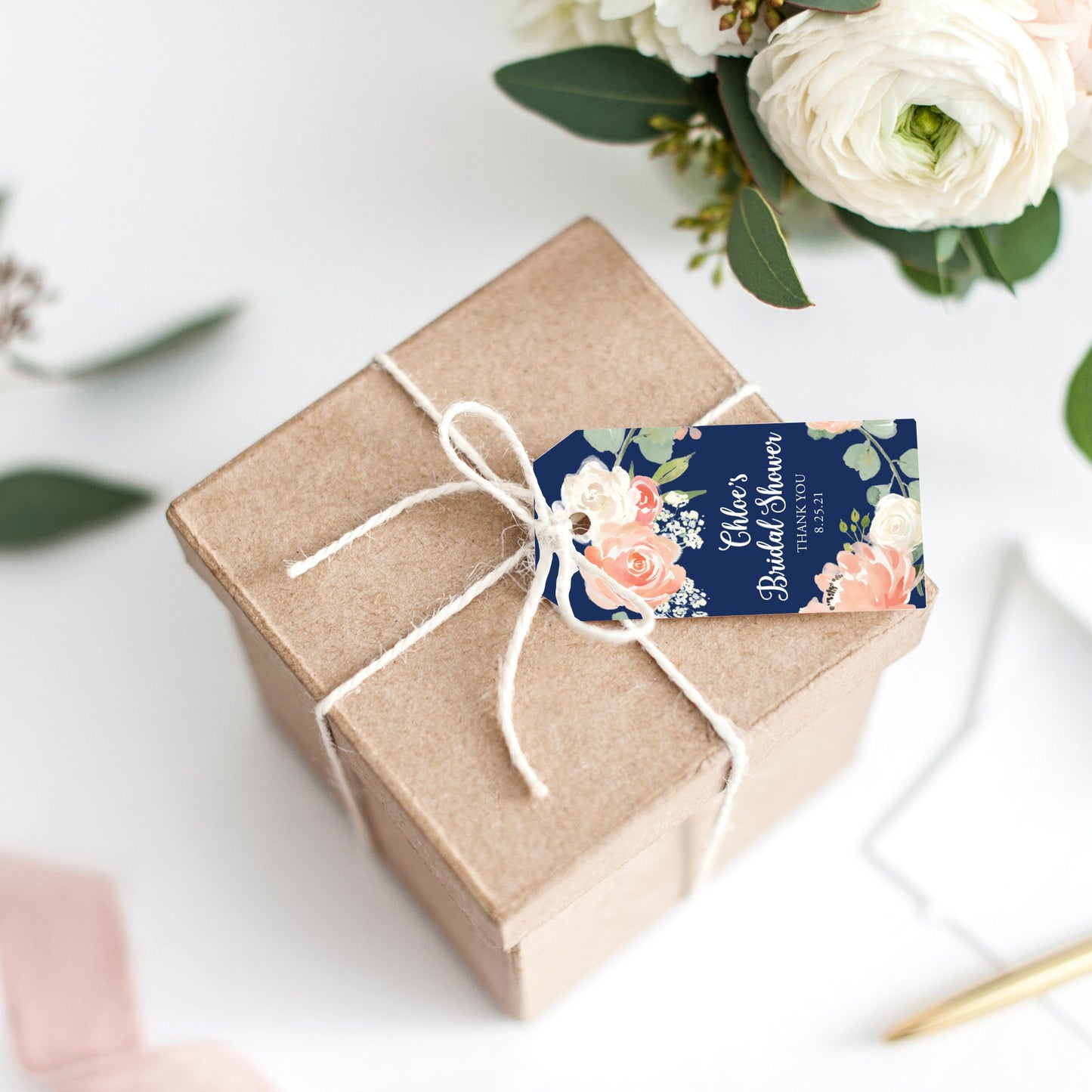 Lux Party’s navy blue bridal shower tag with white script and pastel flowers, tied to a brown kraft favor box.