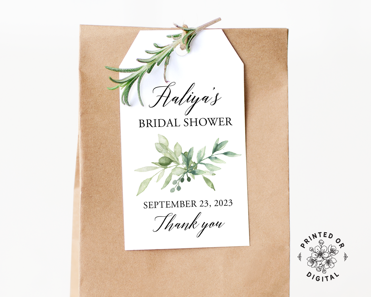 Lux Party’s white bridal shower favor tag with black script and greenery leaves, affixed to a brown kraft favor bag.